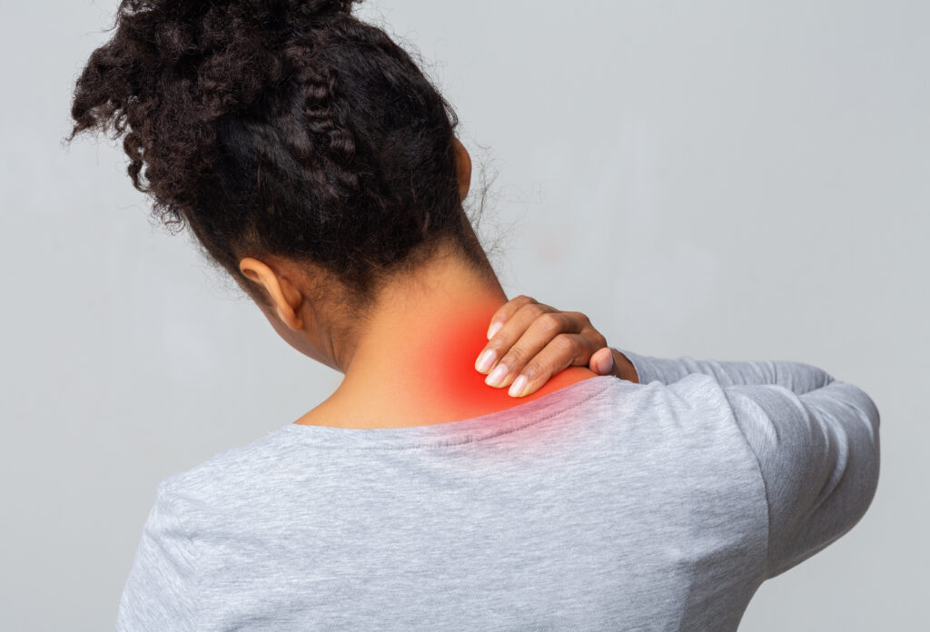 Woman holding the back of her sore neck, with the painful area highlighted in red